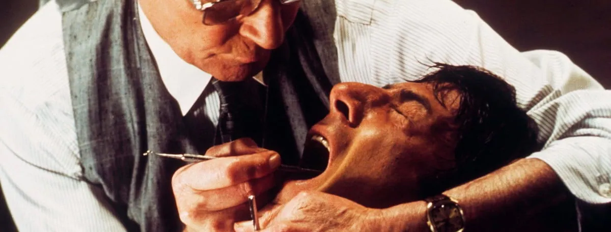 Film still from Marathon Man: the sinister dentist character interrogates a restrained man with a dental pick.