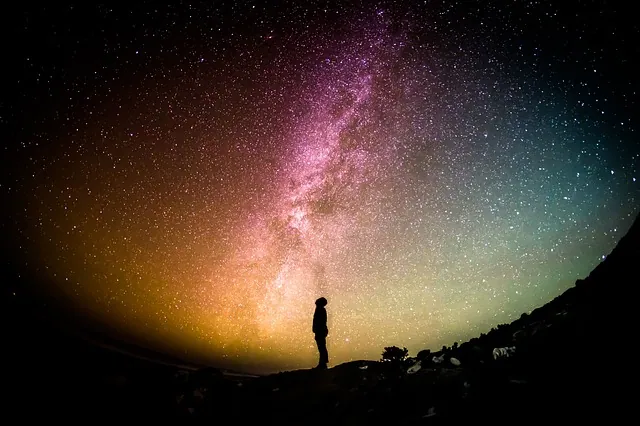 The Milky Way galaxy stretching across a dark night sky above a silhouetted landscape.