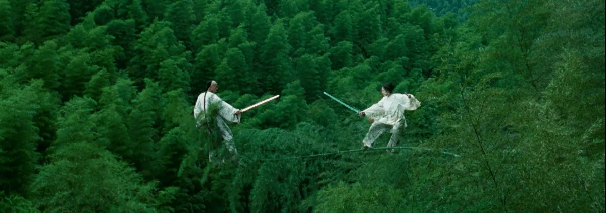 Film still from Crouching Tiger, Hidden Dragon: two swordfighters balance and duel atop swaying bamboo treetops.