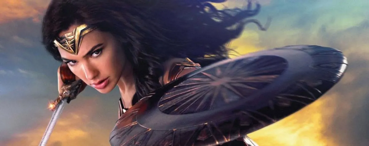 Film still from Wonder Woman: Diana Prince charges into battle with sword and shield raised against a fiery sky.
