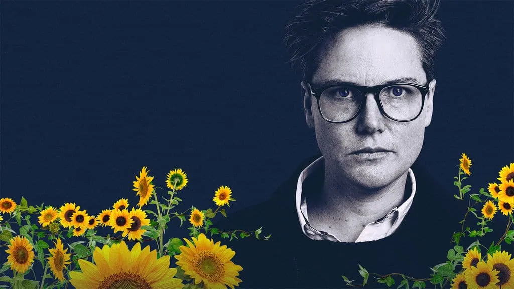Black-and-white portrait of Hannah Gadsby in glasses, key art for her Netflix special Nanette, framed by sunflowers.
