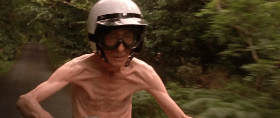 Film still from Waking Ned Devine: an elderly man rides a motorcycle wearing only a helmet and goggles.