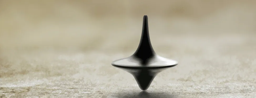 Film still from Inception: the spinning top totem balanced on a table, its ambiguous ending image.