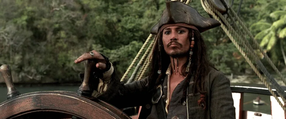 Film still from Pirates of the Caribbean: Captain Jack Sparrow stands at the ship's wheel.