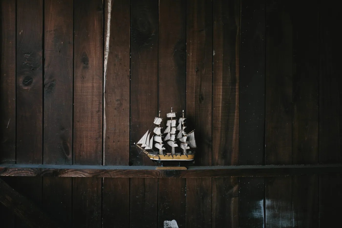 A small model ship adrift in a vast dark space, evoking a story that never leaves the harbor.