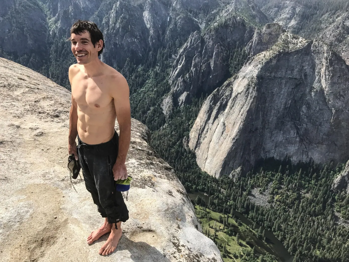 Alex Honnold standing shirtless and smiling atop the summit of El Capitan after becoming the first person to climb it without a rope. (National Geographic/Jimmy Chin)