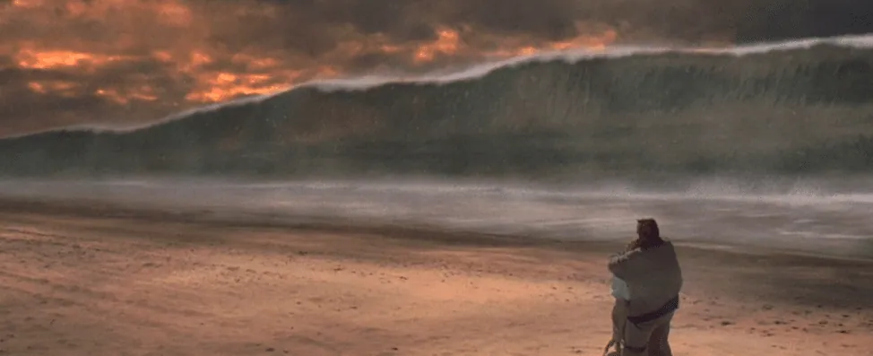 Film still from Deep Impact: a giant tsunami wave looms over a beach as a person embraces another figure at the shore.