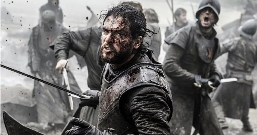 A bloodied warrior gripping two blades, surrounded by armored soldiers in a smoky, chaotic battle.