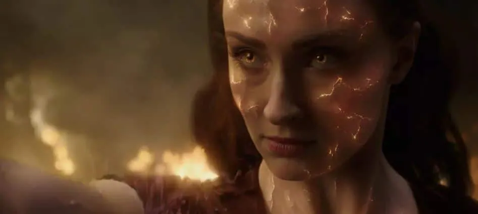 Close-up of a woman's face crossed with glowing fiery cracks, smoke and flame in the background.