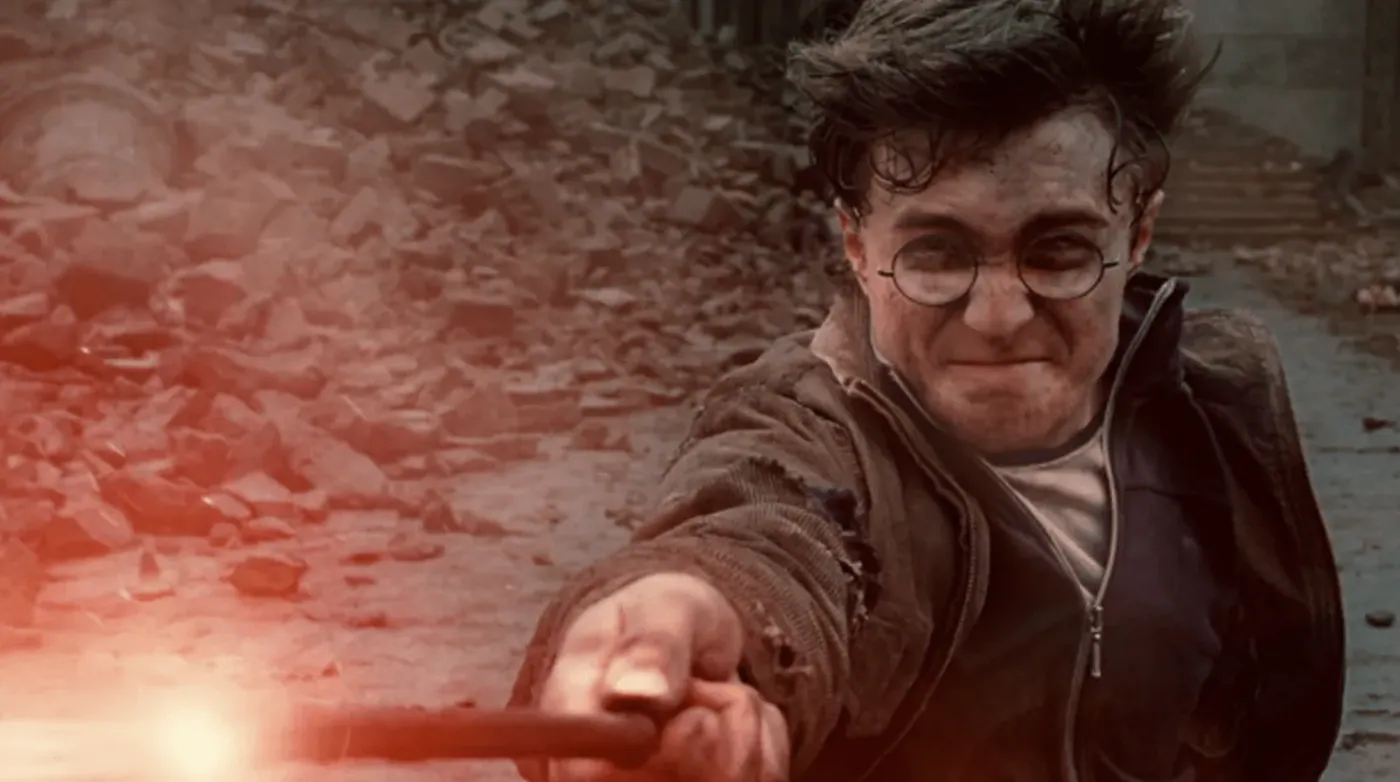 Harry Potter casting a spell with his wand glowing amid rubble, in the climactic battle at Hogwarts.