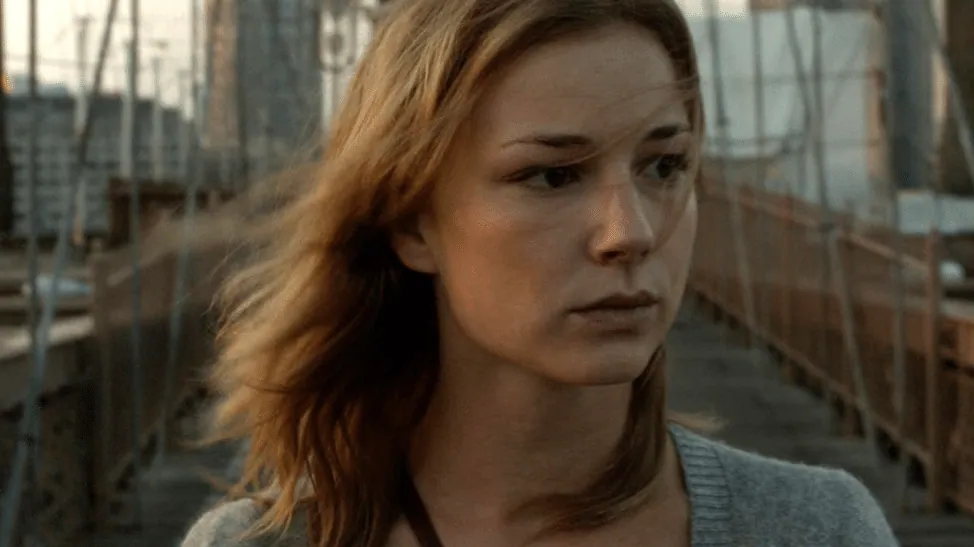 Film still from The Girl in the Book: Alice on the Brooklyn Bridge walkway, hair blowing, looking troubled.