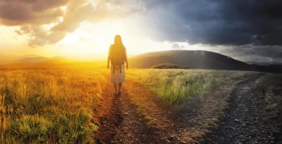 A woman with a backpack walks down a path splitting a golden sunlit field from a stormy grey path, symbolizing conflicting objects of desire.