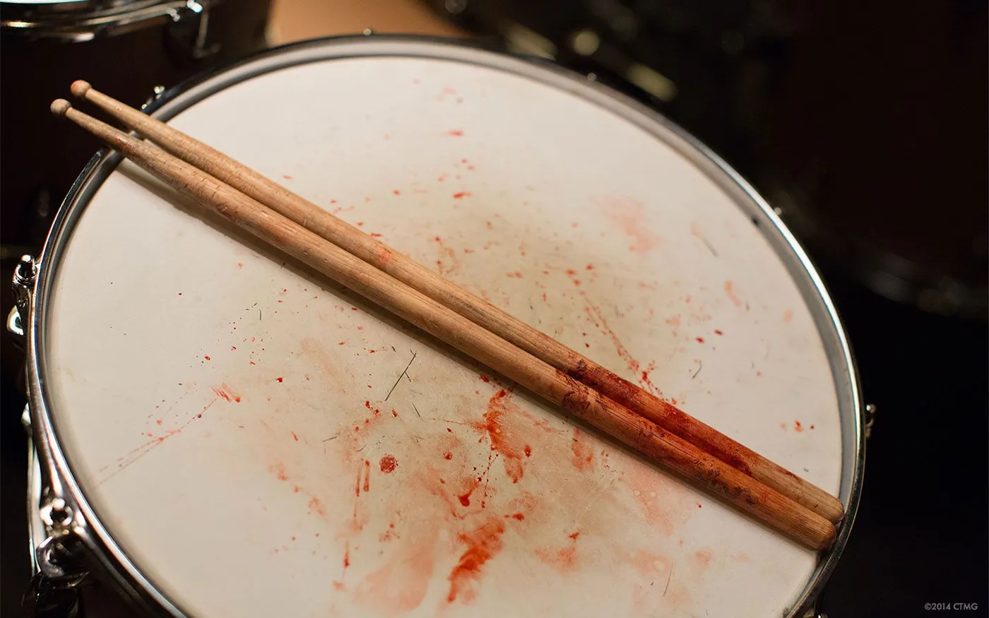 Bloodied drumsticks resting on a snare drum spattered with blood, from Whiplash.