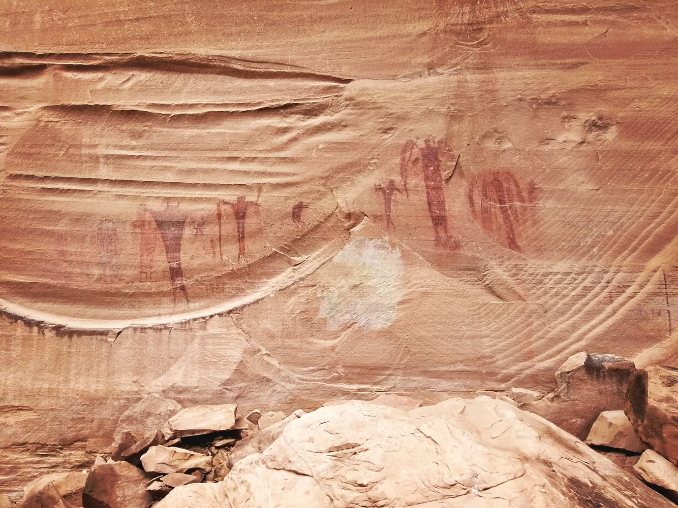 Ancient rock art petroglyphs carved into a stone wall, depicting figures and animals.