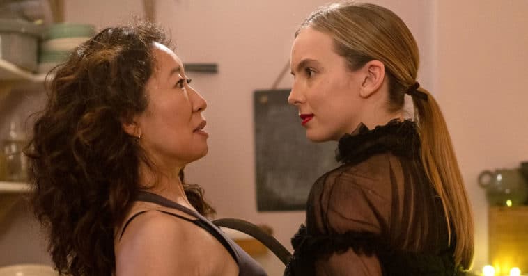 Sandra Oh as Eve and Jodie Comer as Villanelle standing close together in a tense, intimate moment from Killing Eve.