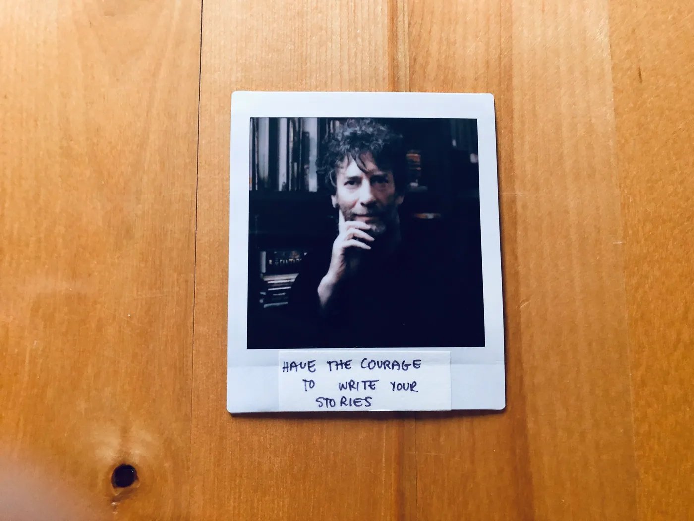 A printed photo of Neil Gaiman pinned above a handwritten note reading "Have the courage to write your stories."