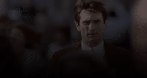 Travis Bickle in a jacket and tie, singled out in sharp focus while walking through a crowd.