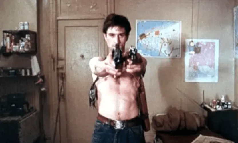 Travis Bickle with a spring-loaded sleeve holster, aiming two handguns in his cluttered apartment.