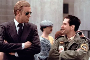 Travis, in his green military-style jacket, chatting with a Secret Service agent in sunglasses at the campaign rally.