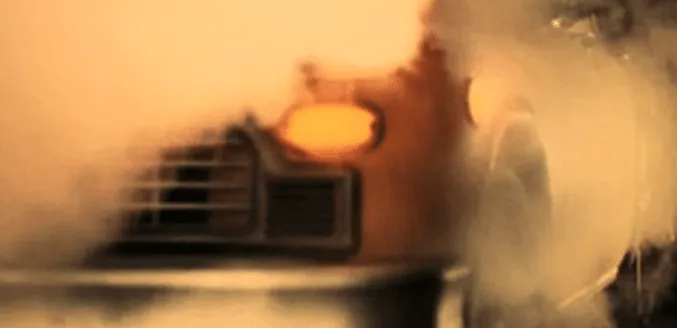 A blurred, rain-streaked view through a car windshield at night, city lights glowing.