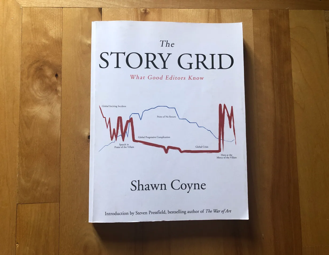 Cover of The Story Grid by Shawn Coyne, photographed on a wooden table.