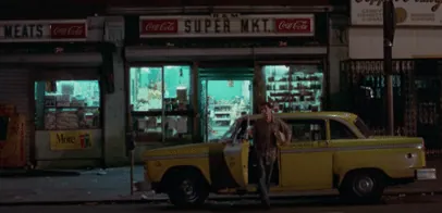 Travis's yellow taxi parked outside a corner supermarket at night.