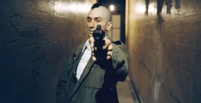 Travis, with mohawk haircut, aiming a pistol down a narrow hallway during the climactic shootout.